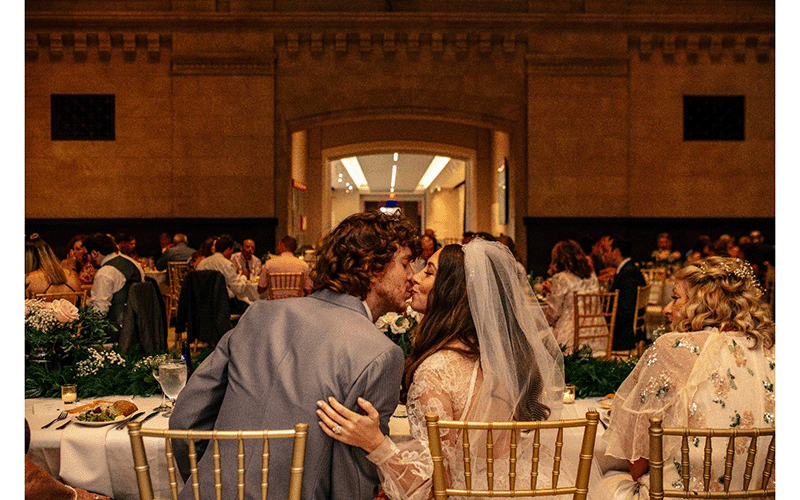 A couple kiss at a table in the Great Hall