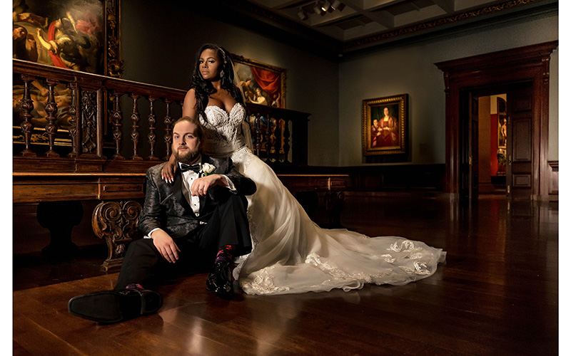 A couple poses for a wedding photo in a gallery