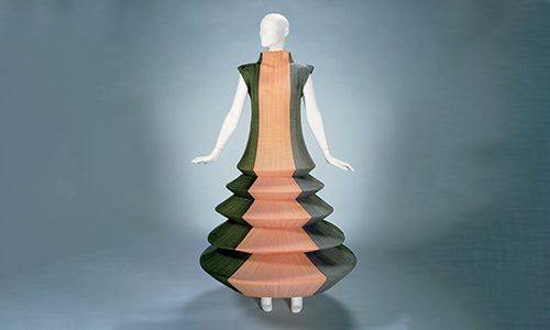 green dress with orange stripe down the middle with saucer shaped layers stacked atop each other