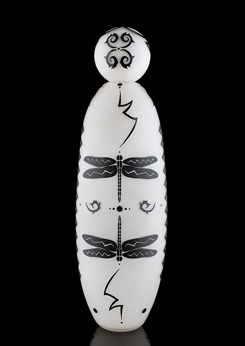 A tall white glass sculpture with a dragonfly design