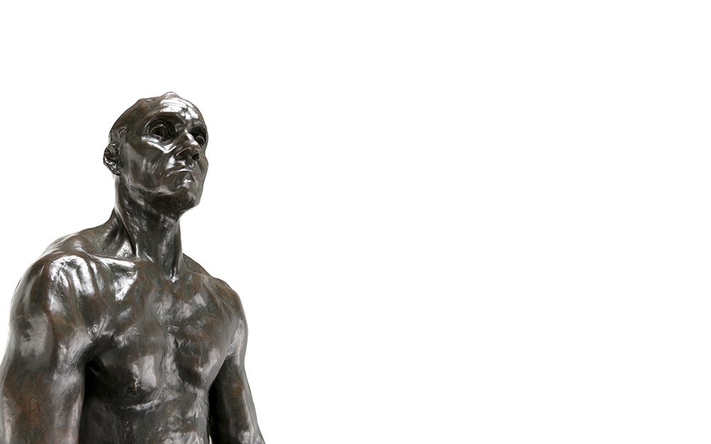 A dark sculpture of a shirtless, muscular man. The man's head is raised and their mouth is downturned.