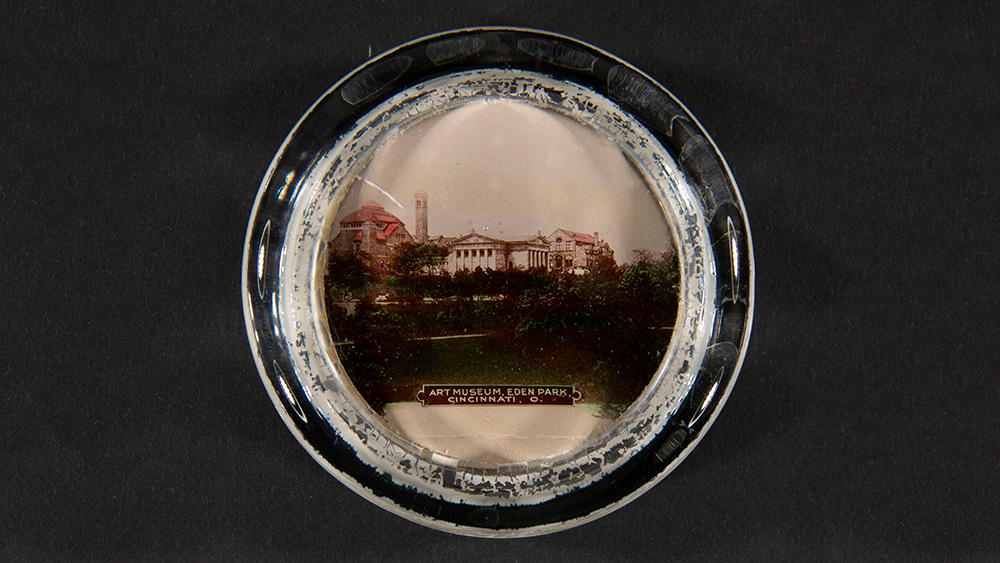 A glass paperweight holds a small photograph of the museum and the Cincinnati Art Academy