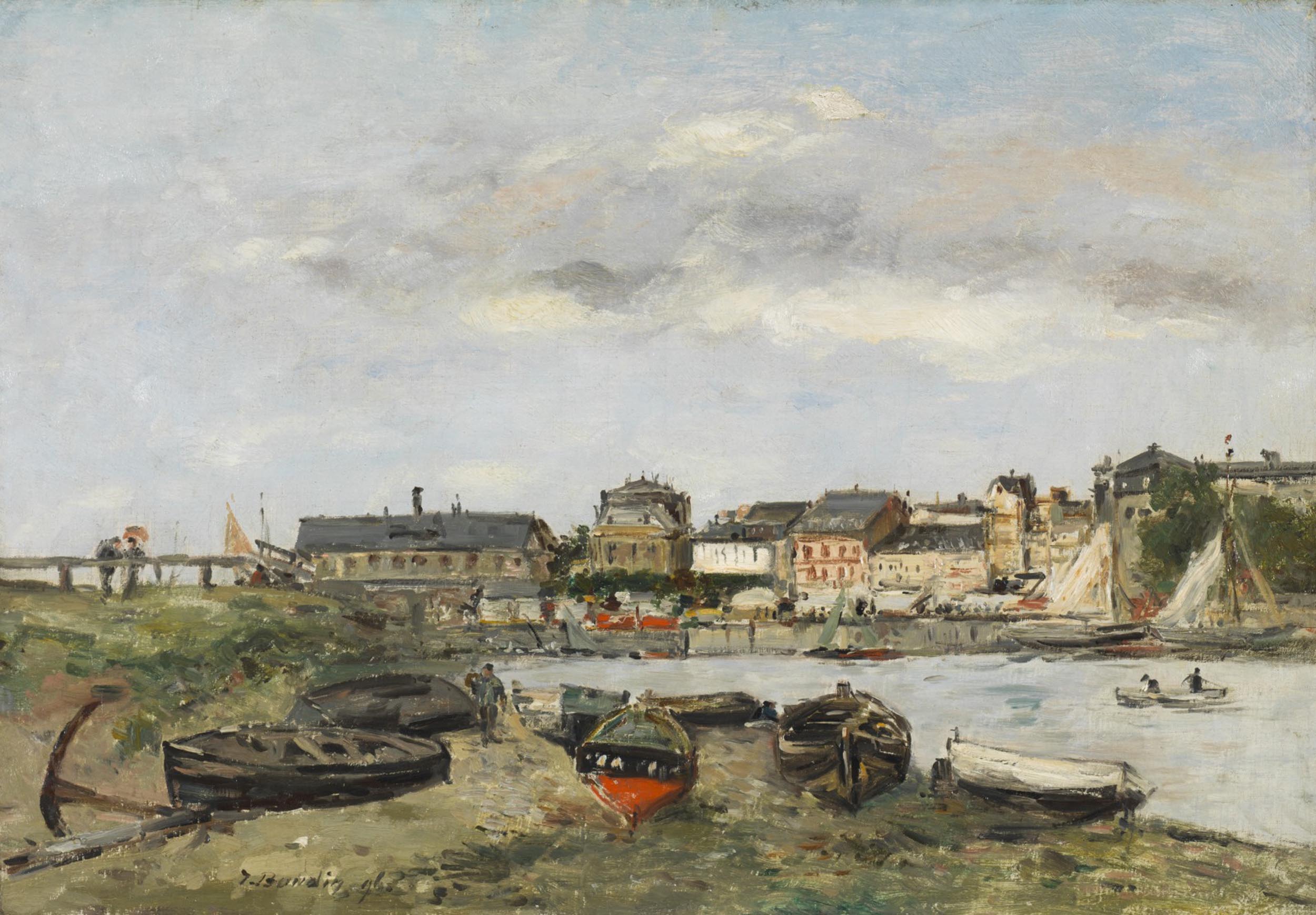 Boats along a riverbank with a town in the background
