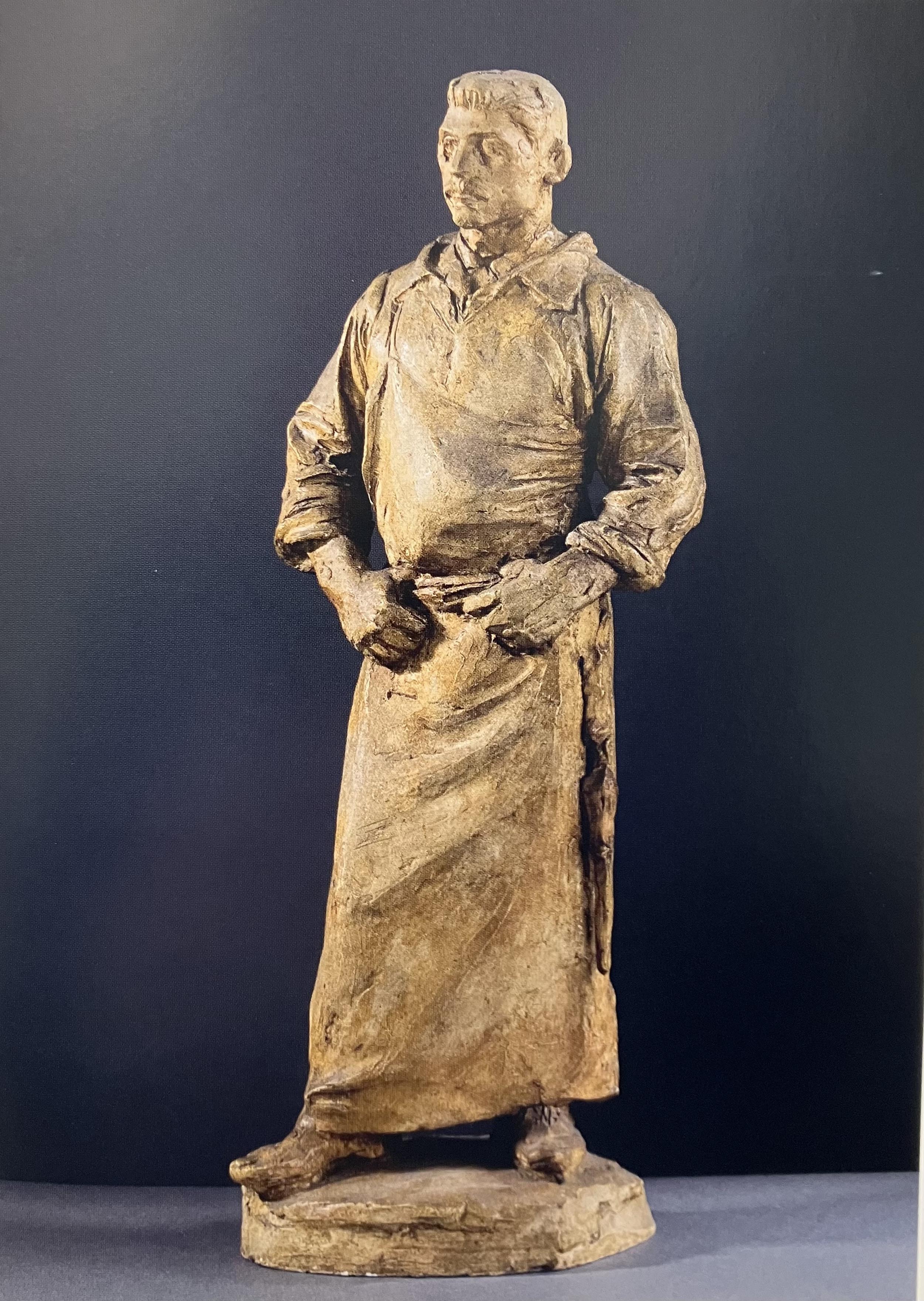 A rough sculpture of a man in an apron