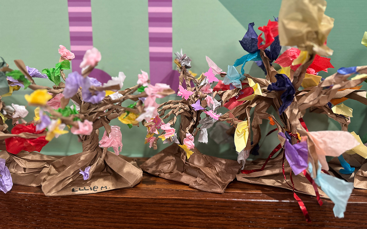 Sculptures -- made of colorful paper and representing tree-like forms -- sit on a wood shelf.