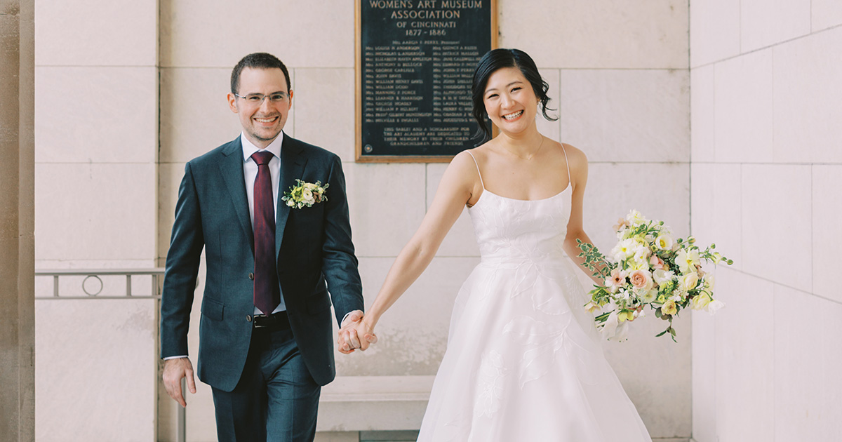 A smiling couple walks toward the photographer by the front entrance of the museum