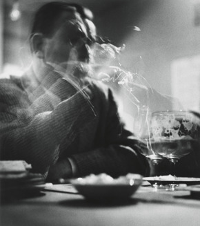 Ralph Eugene Meatyard’s Untitled, blurry black and white photograph of a man sitting at a table taking a drink