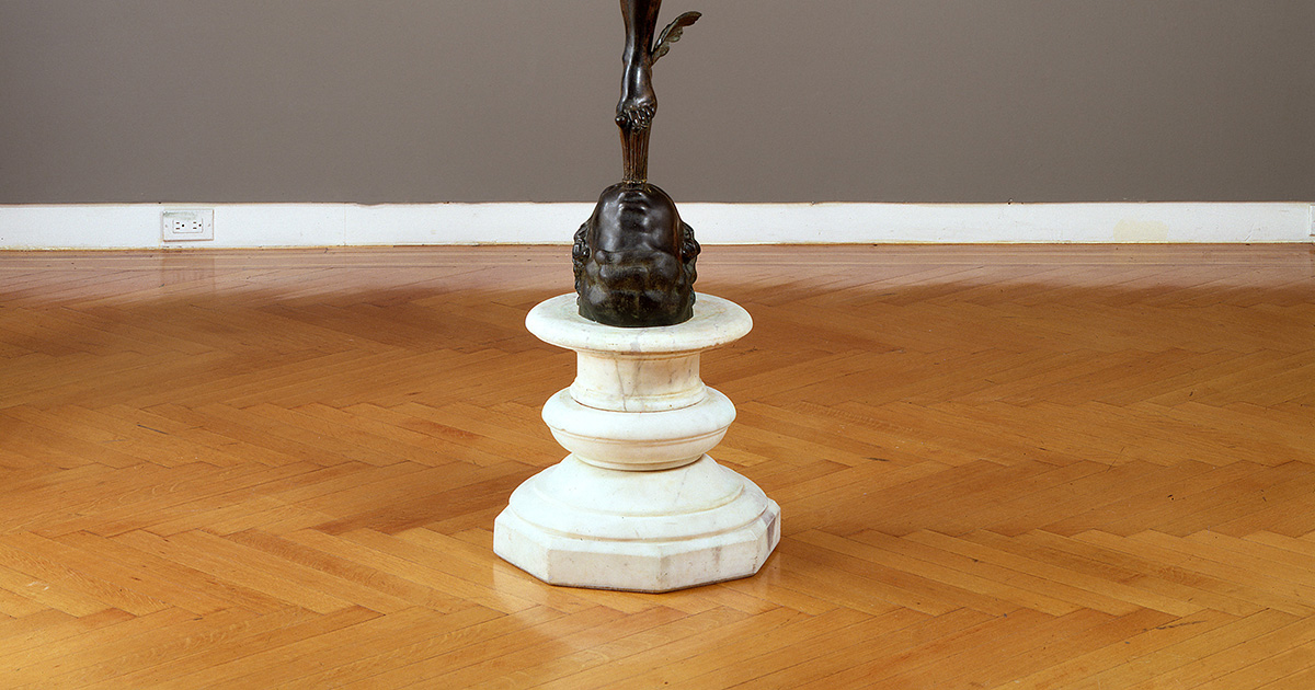 A round marble base under a dark bronze sculpture