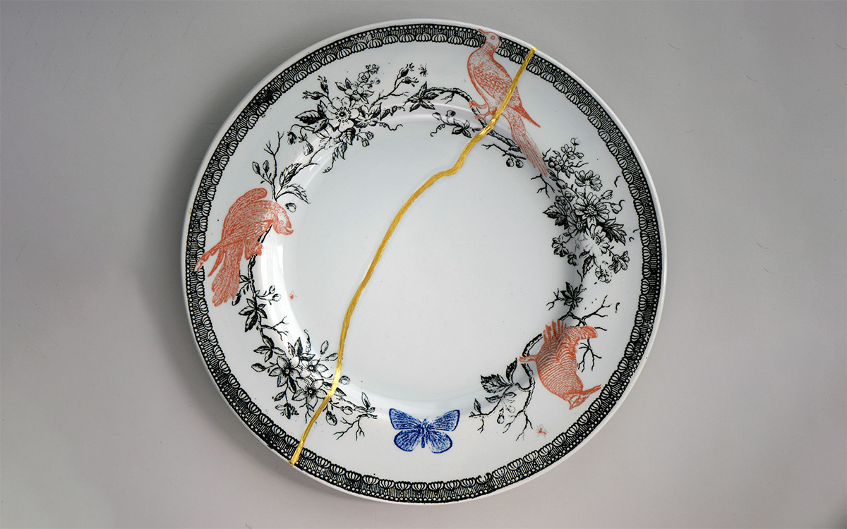 A dinner plate with a crack down the center that has been repaired with gold