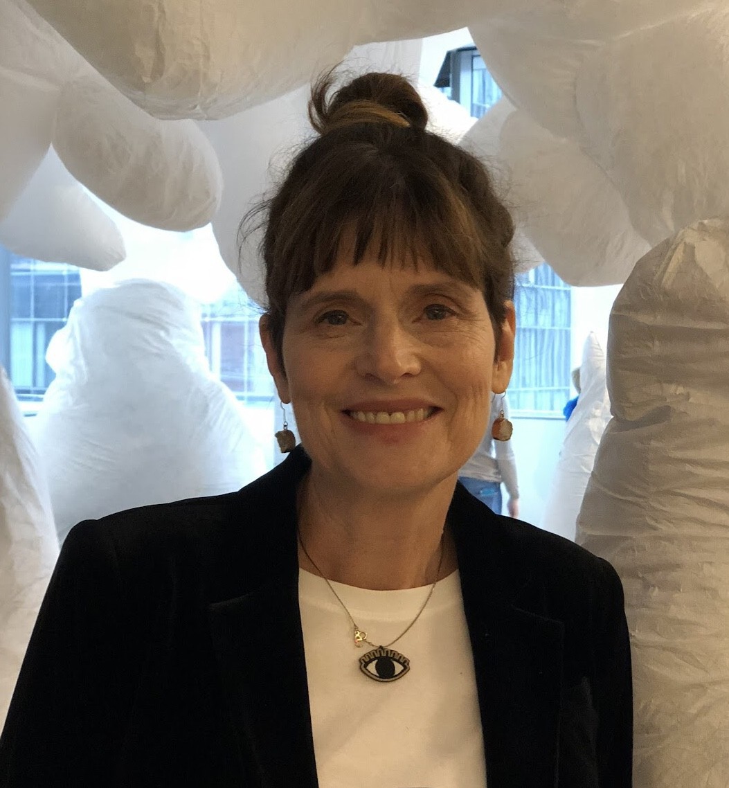 A smiling white woman surrounded by white, fluffy forms