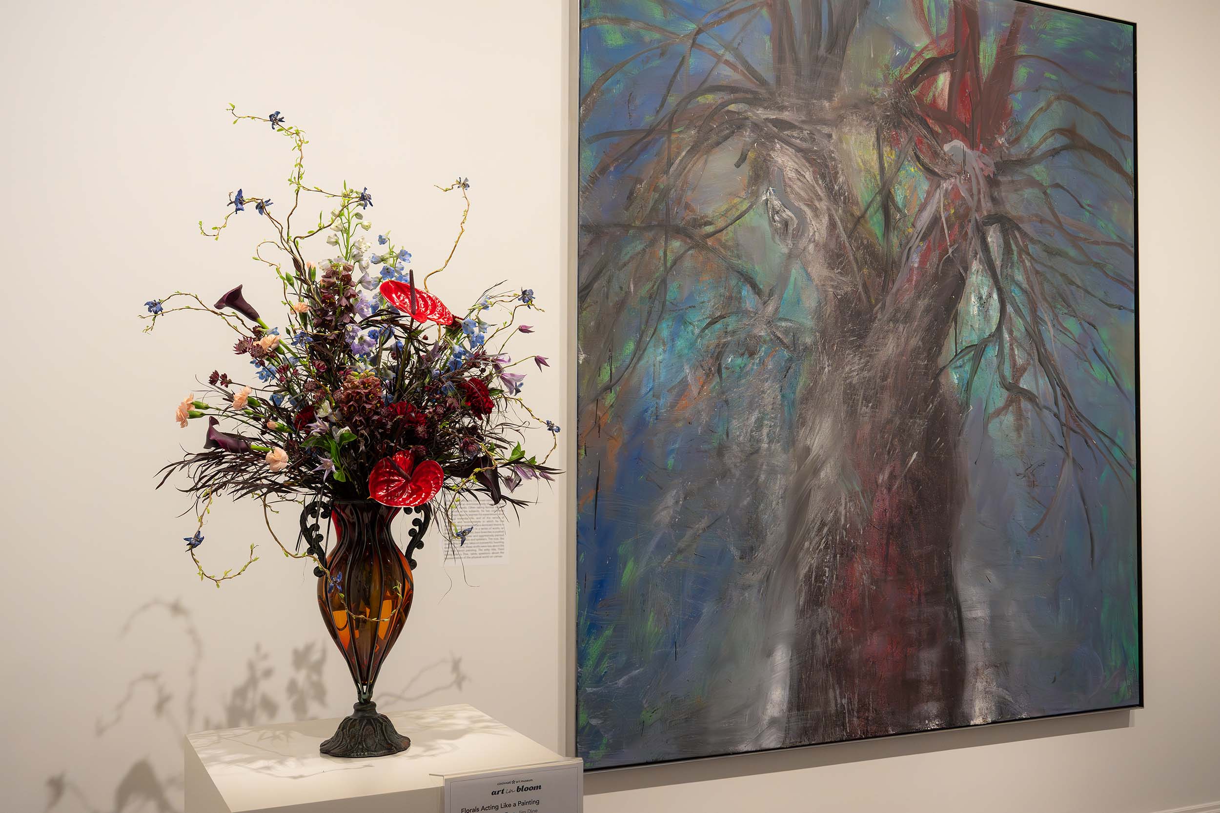A floral arrangement with extended, wispy tendrils and two huge, round red flowers
