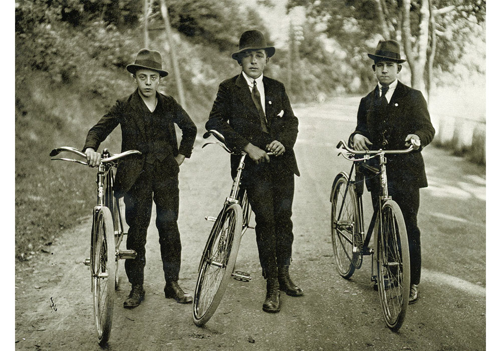 black and white photograph of  three boys posing with their bikes
