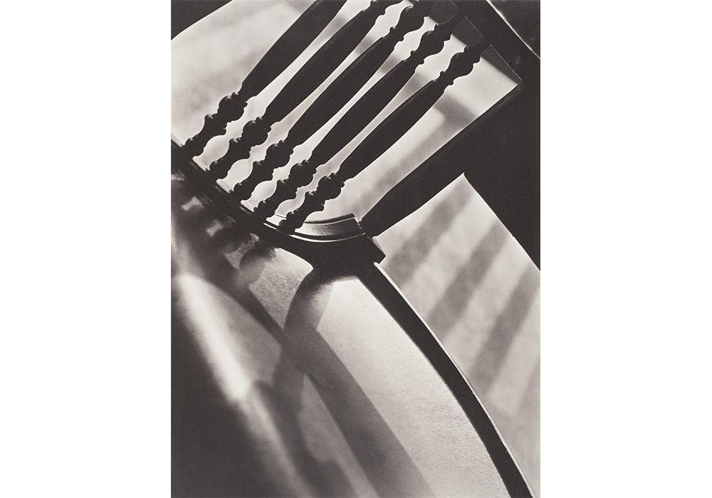 Paul Strand's Chair Abstraction, a close up, black and white, angled photo of a wooden chair