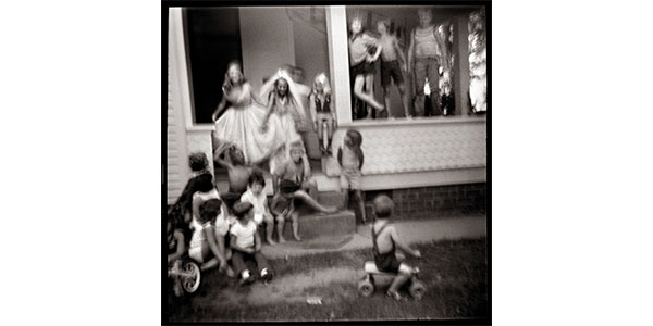 Nancy Rexroth's Group Portrait, black and white photograph of a group of children sitting on a staircase and railing to a porch