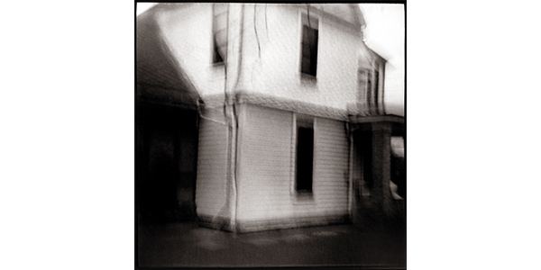 Nancy Rexroth's Waving House, a blurry black and white photograph of a simple, two story house 