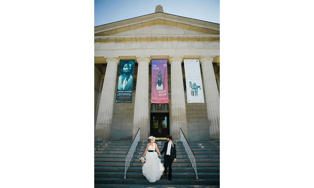 bride and groom on the front steps to the museum