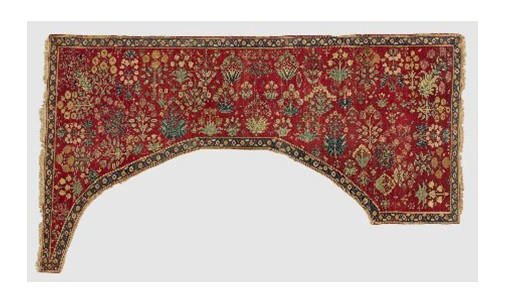Shaped carpet, an oddly shaped, red, floral patterned carpet. 