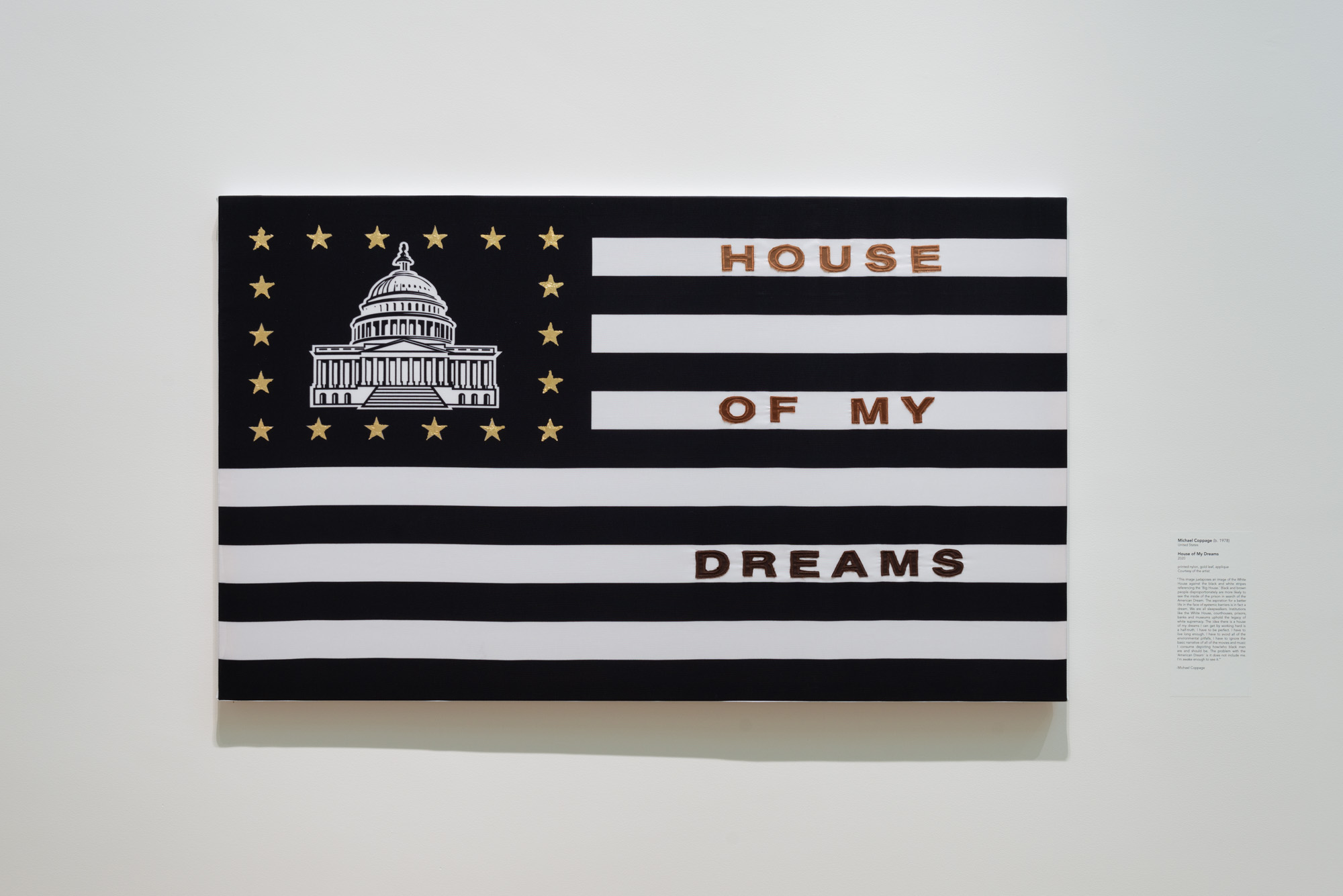 Michael Coppage's House of My Dreams, a black and white American flag with a rectangle of gold starts surrounding a print of the U.S. Capitol building in the top left corner. the words "House of my dreams" in bold, golden lettering are written in between the stripes on the right side