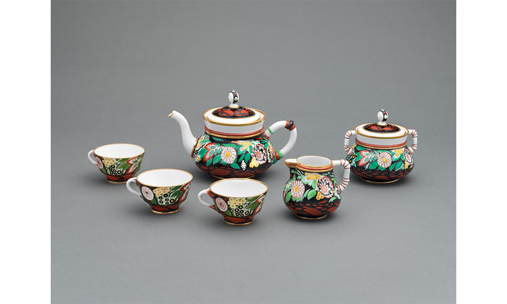 Porcelain tea set decorated with a large floral pattern around the middle of each piece and auburn colored leaves around the bases