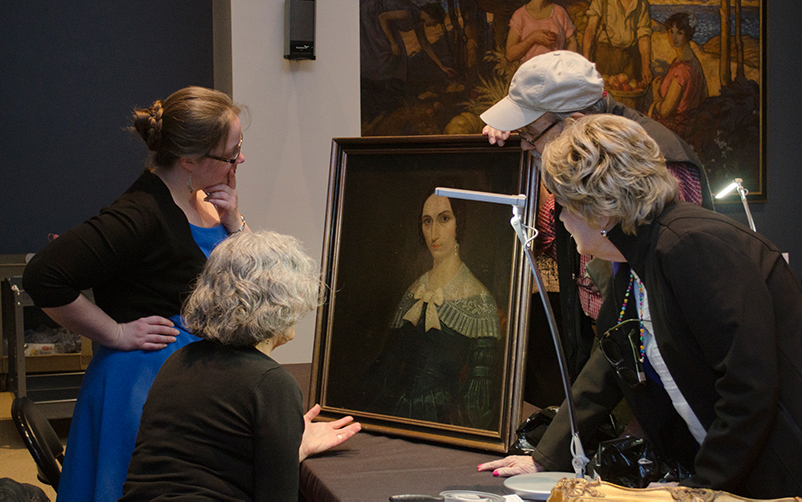 A group of people inspecting a painting