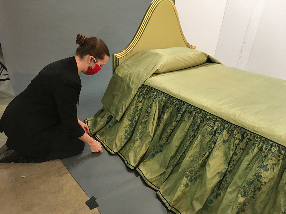Textile Conservator Chandra Obie Linn fixing the skirt of a bedspread from the Wormser bedroom during a photo shoot.