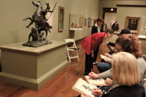 visitors sketching a statue in a gallery