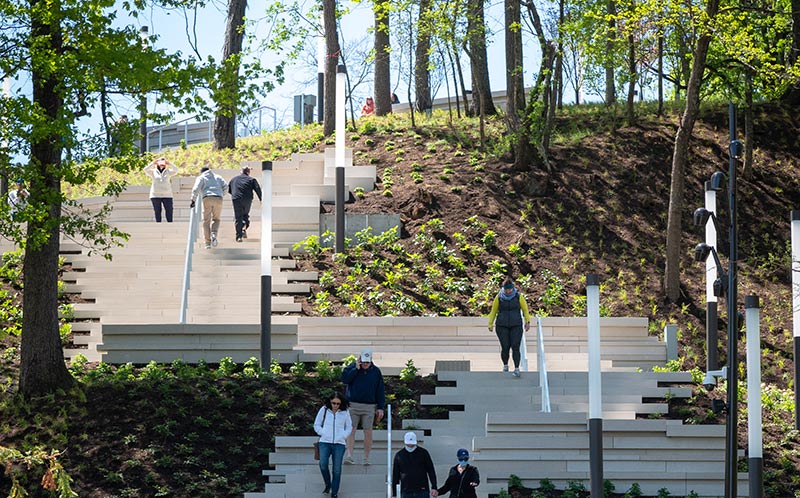 Visitors traverse the Art Climb on a sunny day, surrounded by greenery.