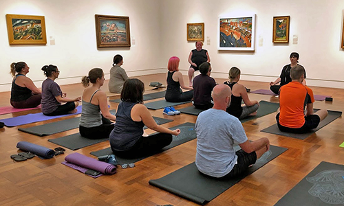 Visitors sit on yoga mats in the gallery
