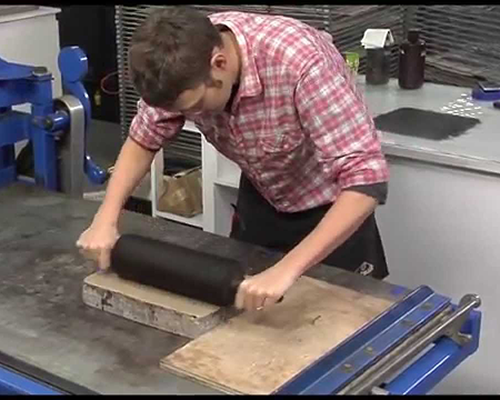 A white man rolls a large stone slab