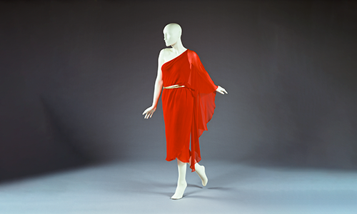A red dress with one shoulder exposed and a drape off the other shoulder