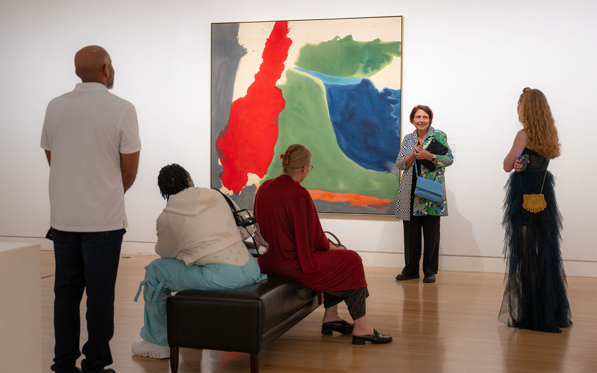 A group of adults look at a massive painting with a guide