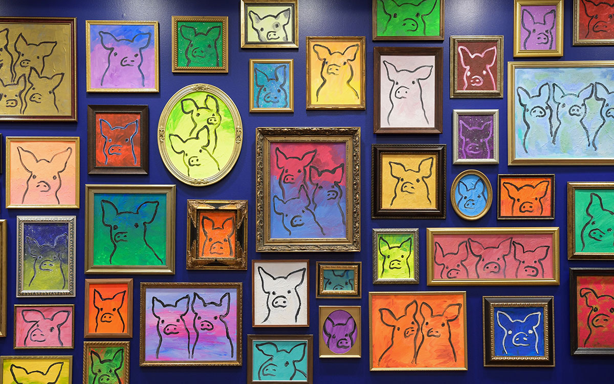 A vibrant display of framed art featuring pigs.