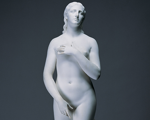 A white marble sculpture of a nude figure covering themself