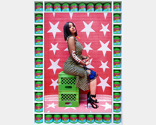Cardi B sits on two green milk crates. The word "unity" is spelled out on her arm.