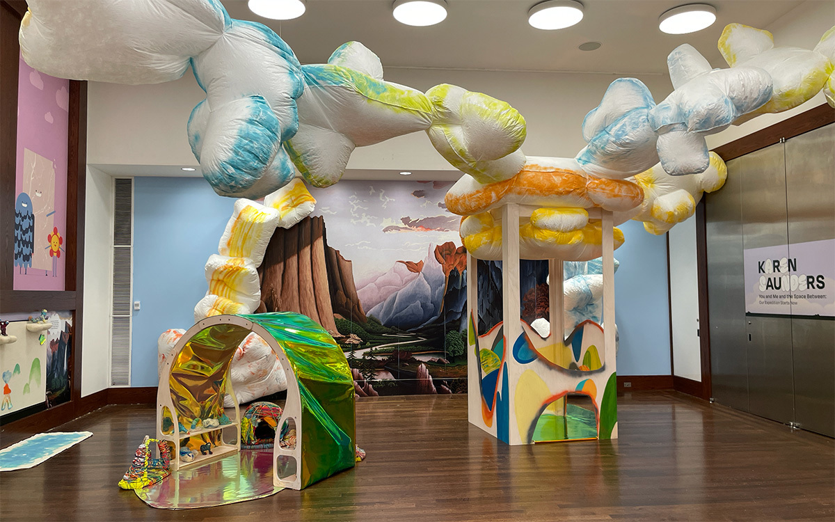 An installation featuring large blue and yellow clouds hanging from the ceiling