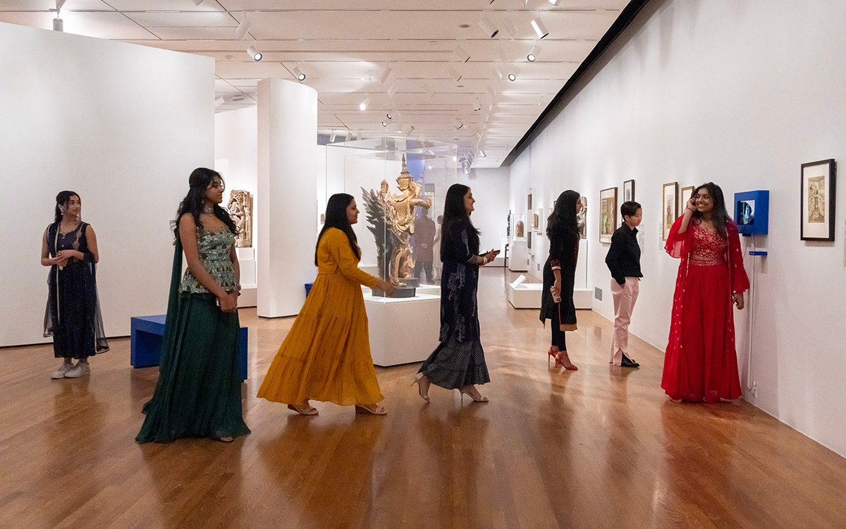 A group of Indian women in gorgeous, colorful dresses explore an exhibition