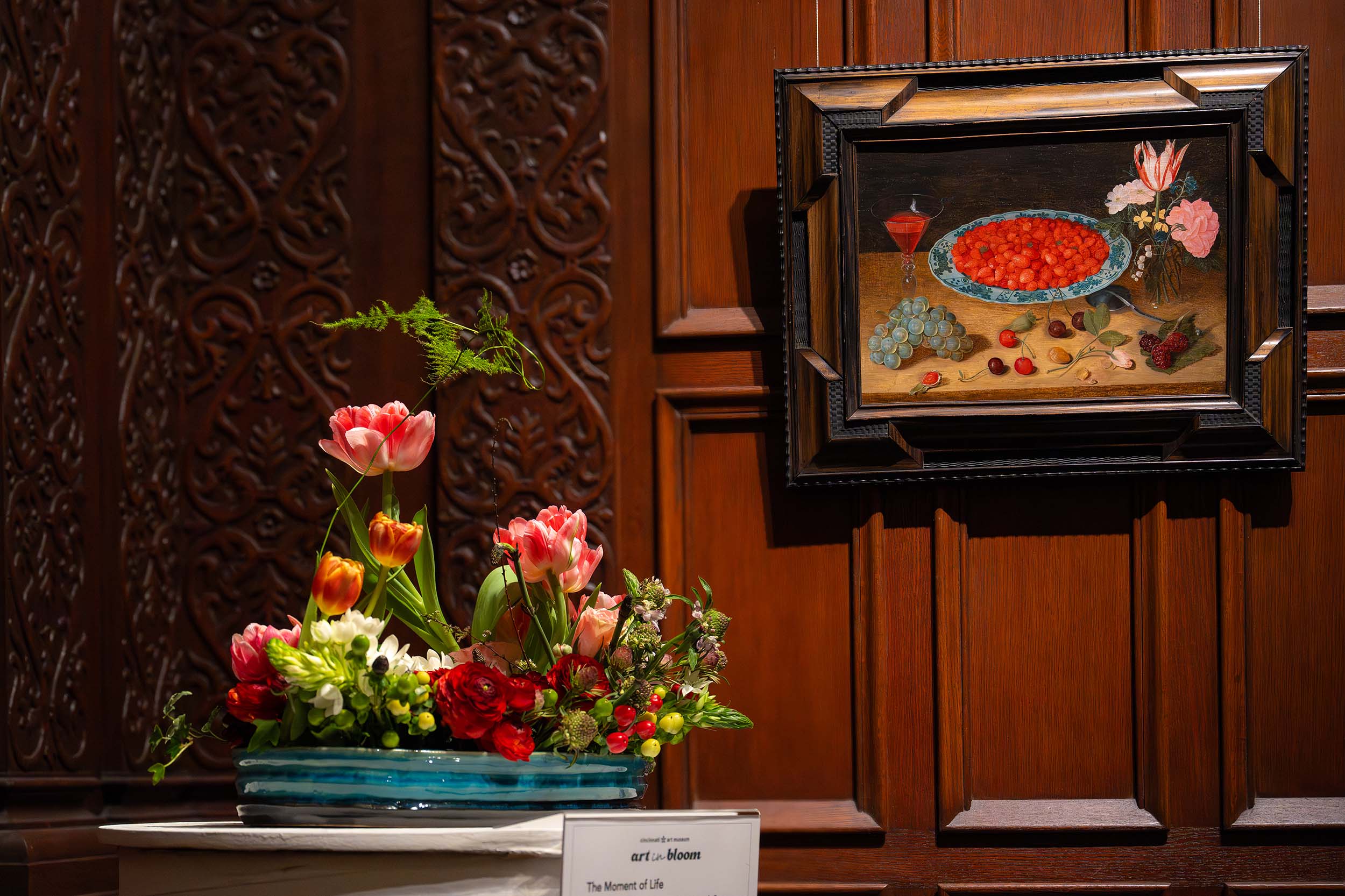 A short floral arrangement with a red base and tall, colorful flowers