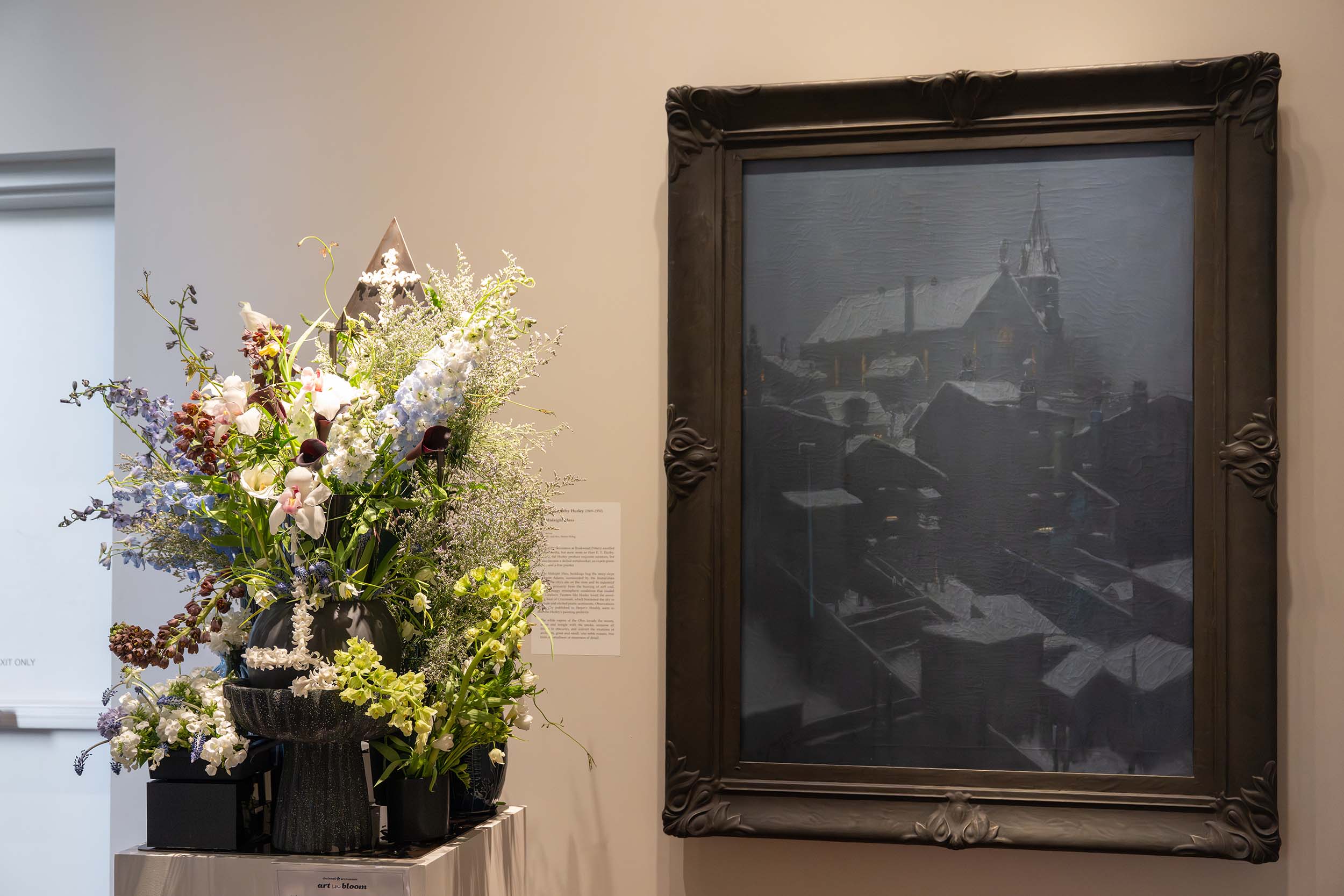 A tall floral arrangement in several small, dark vases with a cross detail on top