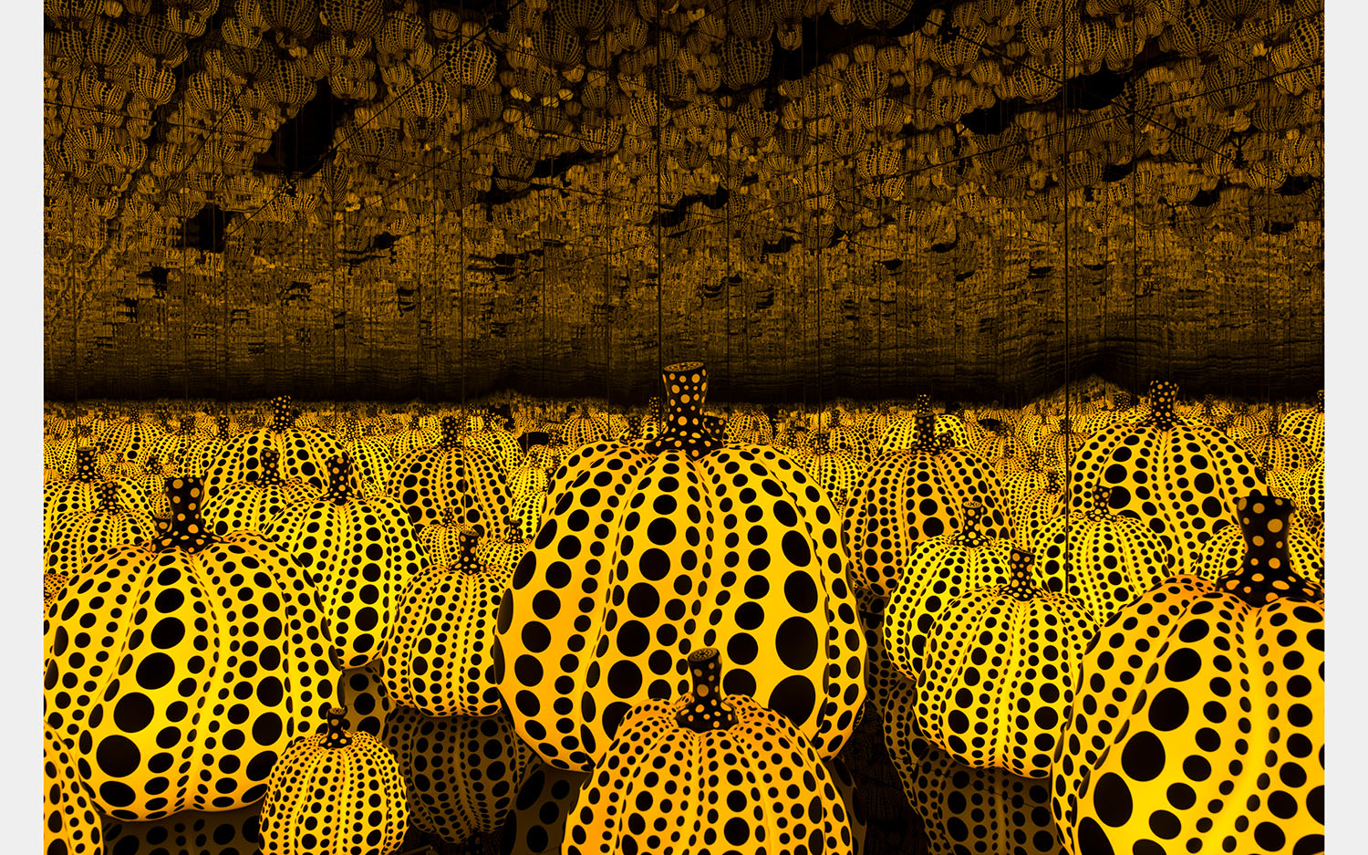 A mirrored infinity room full of yellow and black pumpkins