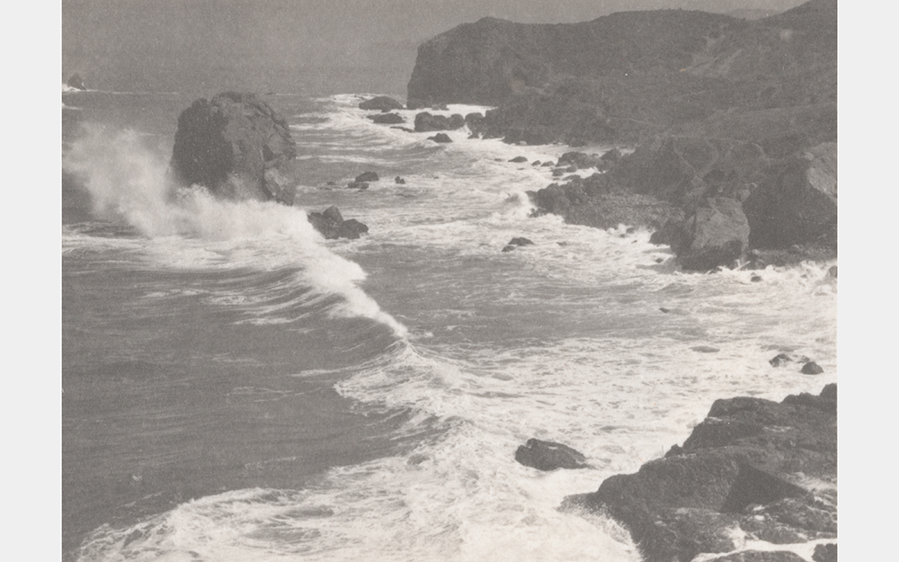 A black and white photo of waves crashing on a rocky shore