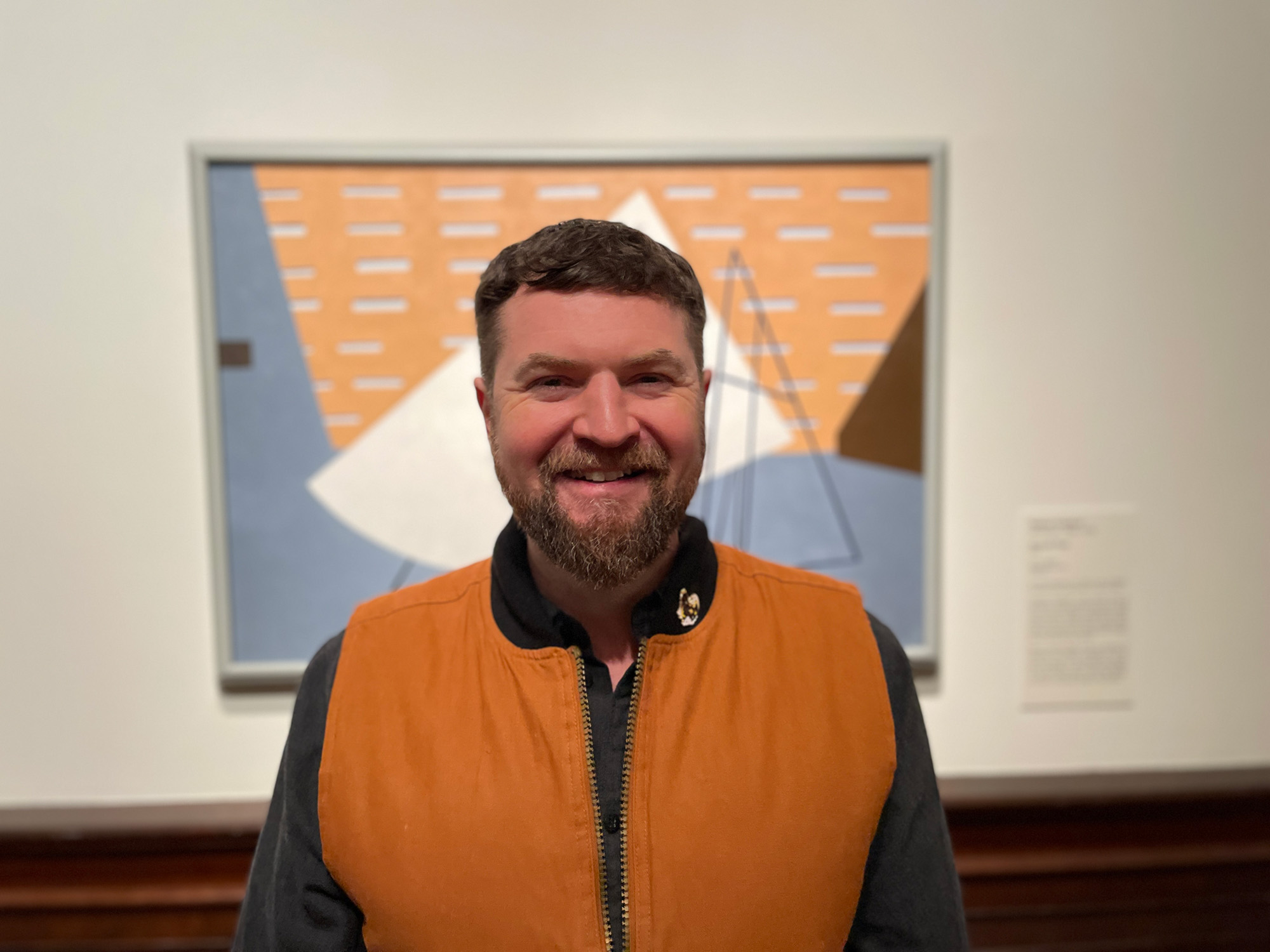 2026 REC Artist in Residence Kenton Brett standing in front of Ralston Crawford’s Aircraft Plant (1949.157) in Gallery 212