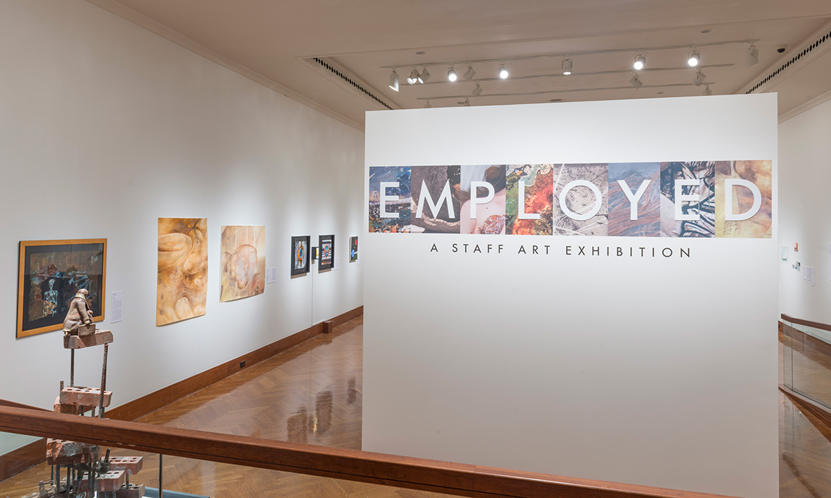The title wall of the exhibition reads "Employed: A Staff Art Exhibition"