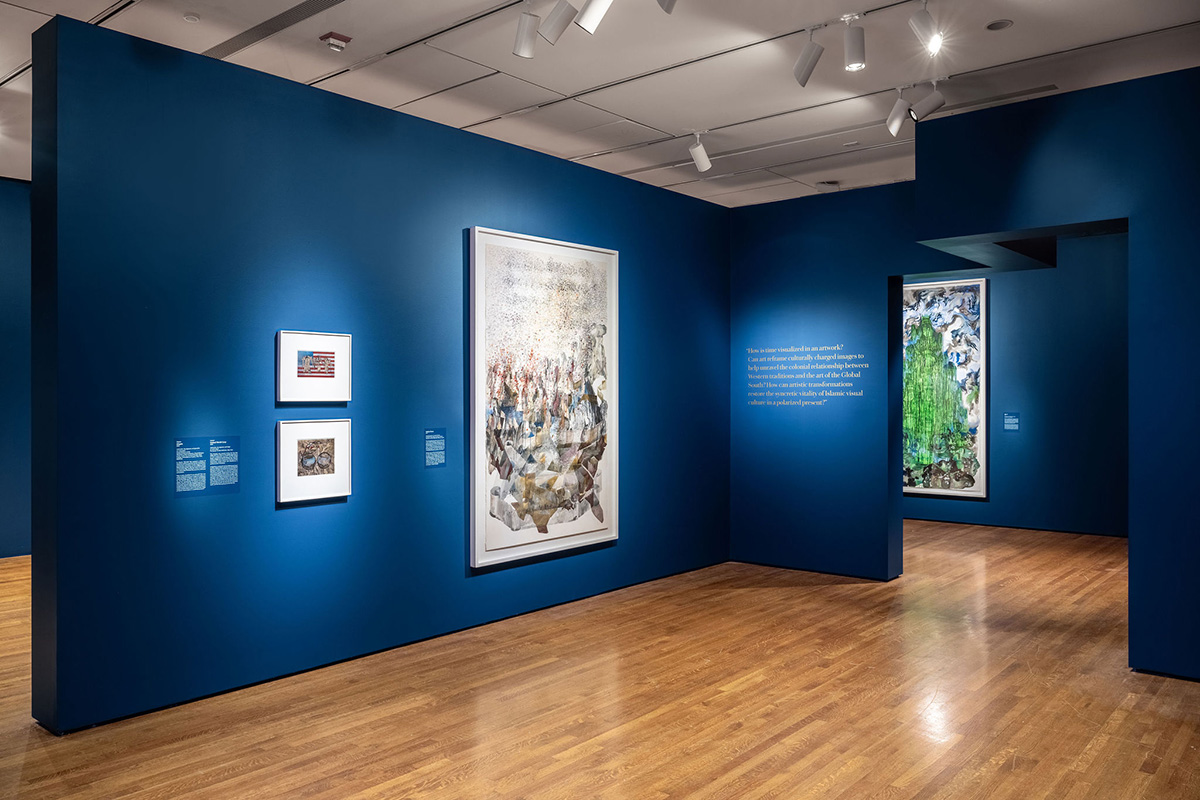 Two small pieces beside one large piece on a blue wall in a gallery