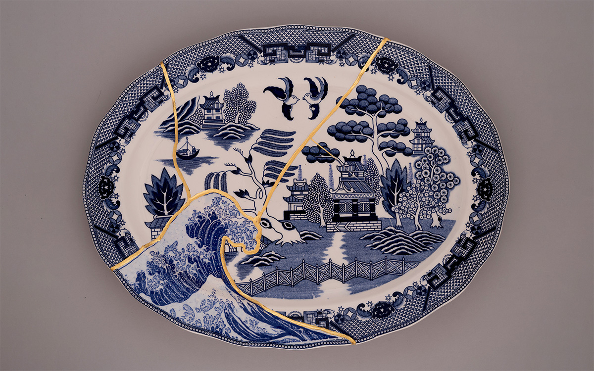 An oval plate with cracks repaired with gold and a large tsunami wave print added