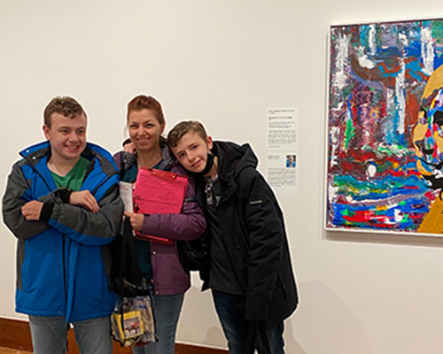 A family hugs in front of an artwork