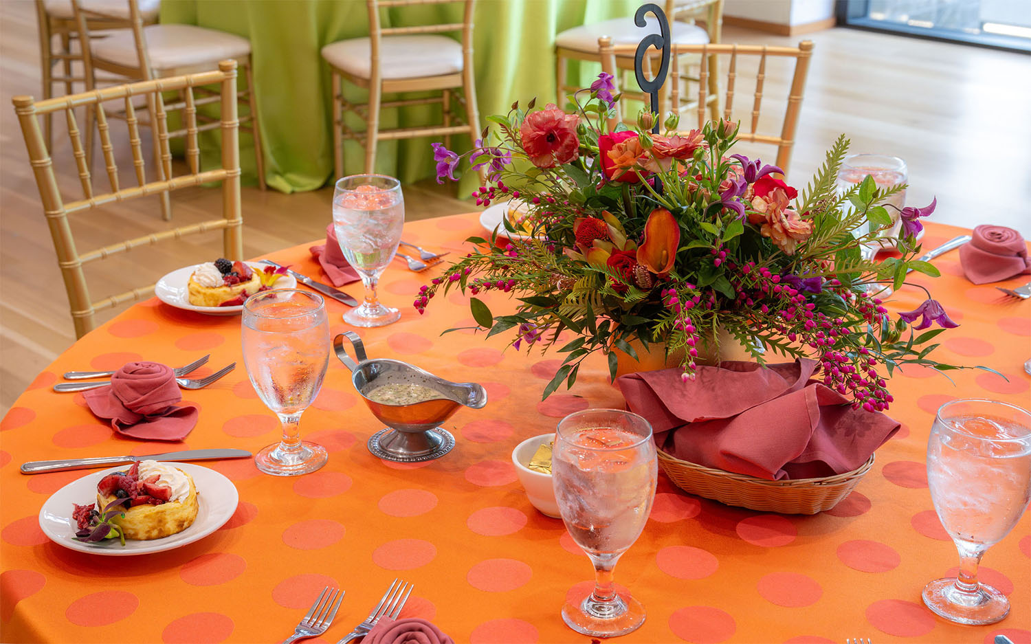 A colorful brunch setup with pastries and a large floral arrangement
