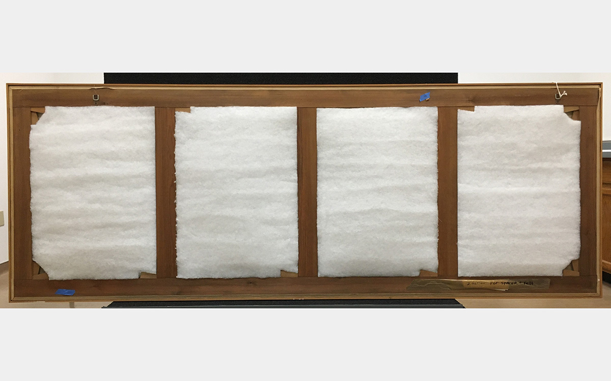 Back of a painting showing batting and back of wooden frame structure.