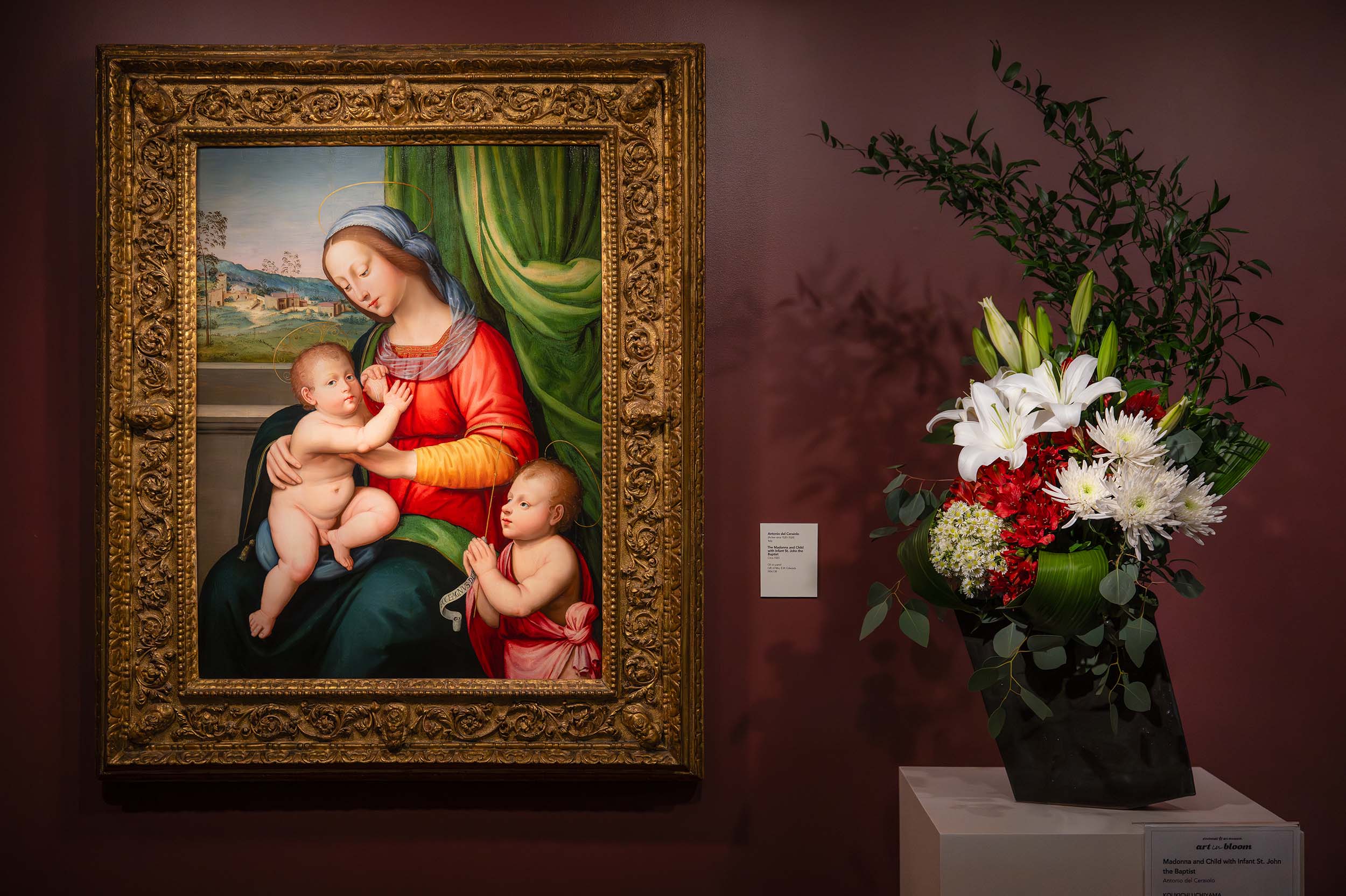 A white and red floral arrangement in a dark, diagonal vase