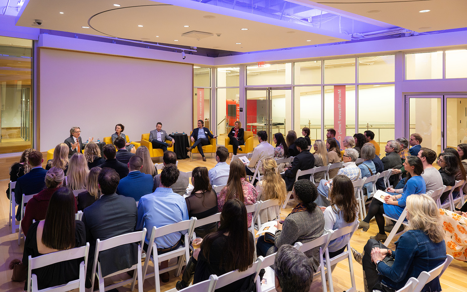 A large audience listens to a panel discussion at the museum