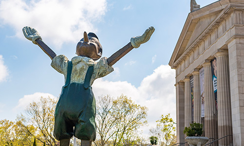 Pinocchio welcomes visitors to the Cincinnati Art Museum main entrance on a beautiful, sunny day.